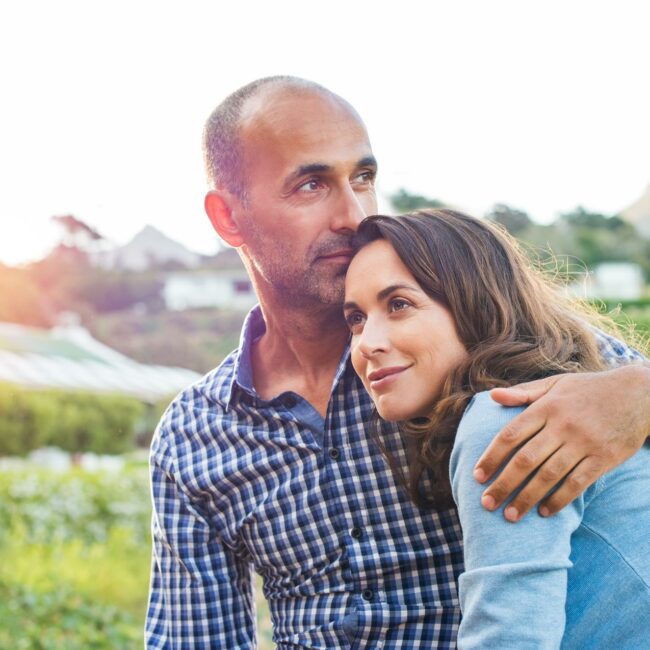 Loving man and happy woman in a spring blooming park. Happy mature couple in love embracing outdoor. Hispanic boyfriend embracing her brunette girlfriend during sunset in a summer day.